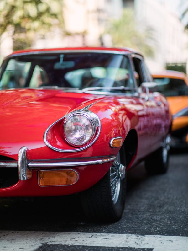 Nahaufnahme eines glänzenden roten Oldtimers, der auf einer Straße in der Stadt geparkt ist.